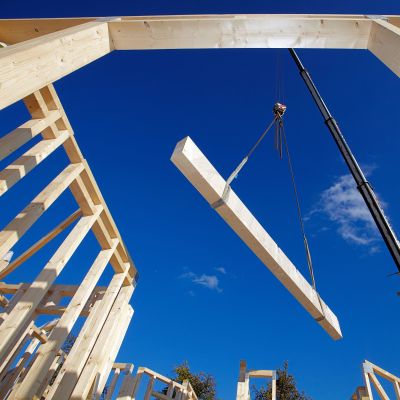 Ein Kran hebt einen Holzbalken auf einer Baustelle