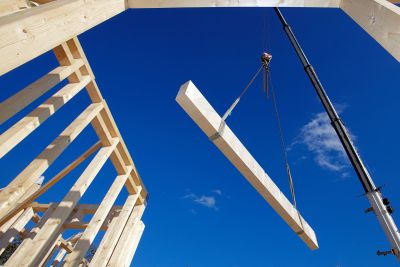 Holzbauoffensive Hessen - Wohnungswirtschaft - Argumente Ein Kran hebt einen Holzbalken auf einer Baustelle