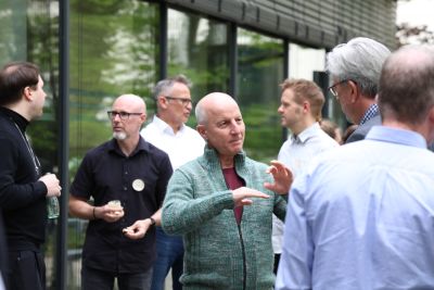 Teilnehmende im Gespräch - Drittes Netzwerktreffen Holzbauoffensive Hessen Teilnehmende einer Veranstaltung, die sich vor einem Gebäude unterhalten.