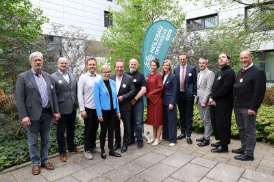 © Sandra Hauer | Gruppenfoto Drittes Netzwerktreffen Holzbauoffensive Hessen Gruppenfoto vor einer grünen Beachflag mit der Aufschrift "Holzbau Offensive Hessen"